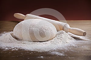 Wooden rolling pin with dough and dusting of flour