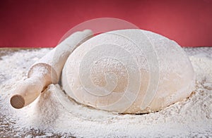 Wooden rolling pin with dough and flour