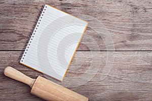 Wooden rolling pin and lined paper on wooden table top view