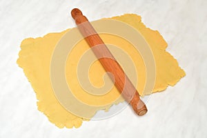 Wooden rolling pin and rolled out dough for pie or cookies