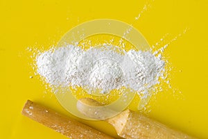 wooden rolling pin and white wheat flour on the table, equipment and ingredients for cookings