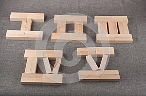 Wooden roman numerals made of toy bricks lay on grey fabric background