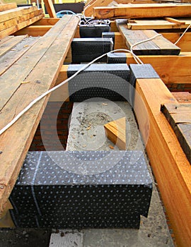 Wooden roof beams installation isolated with bitumen waterproofing barrier on a concrete wall of the house while roofing