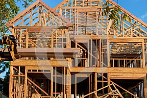 A wooden roof truss being lifted by a boom truck forklift in the roof a new home