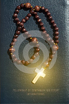 Wooden rosary in the aureole of the divine of Divine Rays on a b