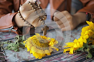 Wooden Rosary in hand. Young junior lady in strong prayer pose. Female hands holding a rosary with Jesus Christ Cross Crucifix.