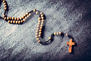 Wooden rosary laying on stone background
