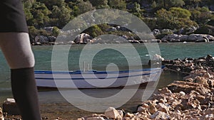 A wooden row boat tied up to a natural stone pier