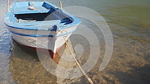 A wooden row boat tied up to a pier