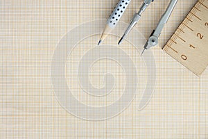Wooden ruler, compasses and pencil lie on graph paper