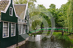 Wooden rural buildings with wooden bridge and trees. Idyllic countryside landscape. Beautiful houses near canal.