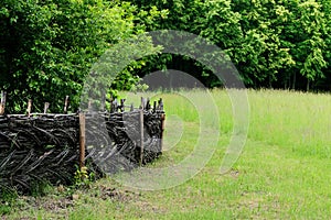 Wooden rural fence in village near the house near the forest. Authentic traditional culture in architecture and life. Old wooden