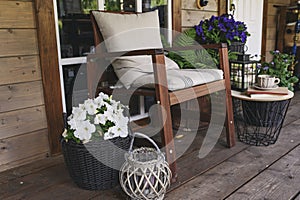 wooden rustic cottage porch with chair, potted flowers and decoration.