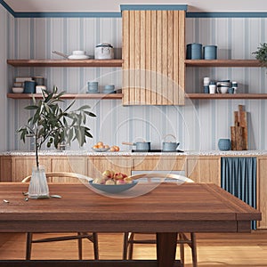 Wooden rustic kitchen and dining room in white and blue tones. Cabinets and table with chair. Wallpaper and parquet floor.