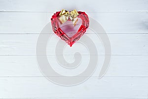 Wooden rustic red decorative heart hanging on white wooden background with space, flat lay. Valentine`s background