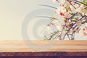 wooden rustic table in front of spring cherry blossoms tree. product display and picnic concept.