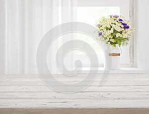 Wooden rustic table in front of wild flowers on windowsill