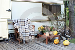 Wooden RV house porch with garden furniture. Campsite in summer garden. Interior yard campsite with flowers potted and pumpkins