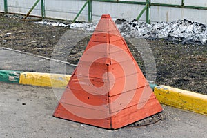 Wooden safety cone stands on a sewer manhole