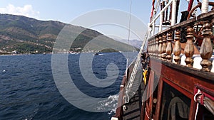 Wooden sailboat floats on the sea to the mountains