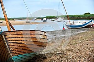 Wooden sailboat on the shingle beach at Brancaster Staithe in Norfolk, UK