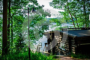 A wooden sauna in the forest on the shore of lake, Finland on a sunny summer day