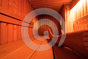 Wooden sauna from the inside with a man taking a sauna