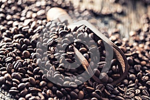 Wooden scoop full of coffee beans on old oak table