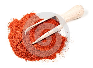 Wooden scoop on pile of paprika powder on white