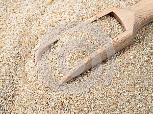 Wooden scoop in rye bran close up