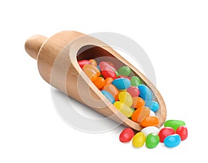 Wooden scoop of tasty jelly beans on background