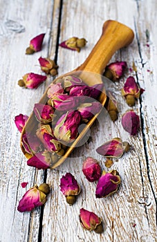 Wooden scoop with tea buds of roses