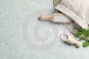 Wooden scoops with natural sea salt and sack on light grey marble table. Space for text