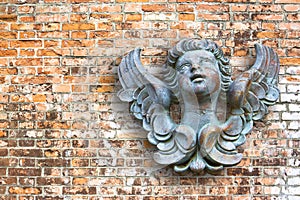 Wooden sculpture of an italian angel against a brick wall - image with copy space