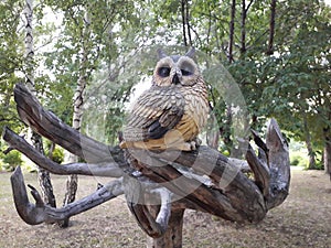 Wooden sculpture owl, on a beautiful snag.Park decoration.