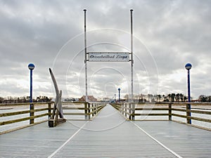 Wooden sea pier at misty morning with light posts. Heavy mist