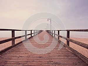 Wooden sea pier at misty morning with light posts. Heavy mist