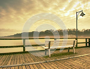 Wooden sea pier at misty morning with light posts. Heavy mist