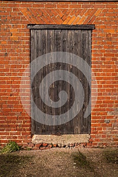 A wooden seasoned door in a brick out farm building