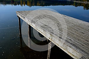 wooden seating area with benches lined with natural wood by the water.