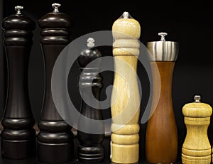Wooden set of salt and pepper grinders on a black background.