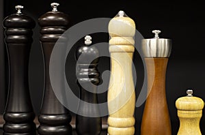 Wooden set of salt and pepper grinders on a black background