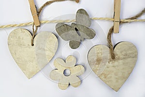 Wooden shaped hearts on the rope with a flower and butterfly isolated on white background