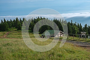 Wooden  shed  in Jeseniky mountains on a summer foggy morning and  sea of clouds around mountain peak