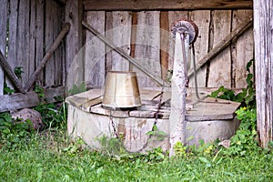 A wooden shed with a wooden lid of a water well and a metal bucket on it