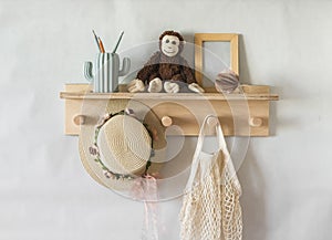 Wooden shelf in the children`s room on the wall with toys, a children`s straw hat, a bag. Interior concept