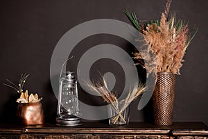 Wooden shelf with different home related objects on the dark wall background