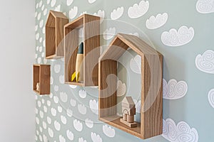 Wooden shelf, rack decoration, kid`s room, whit vintage rocket toy, on green pastel wallpaper angle view