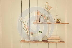 Wooden shelves with books and flowers on the wall