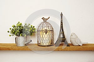 Wooden shelves decorated with Eiffel tower souvenir, candle light, flower bouquet and bird statue